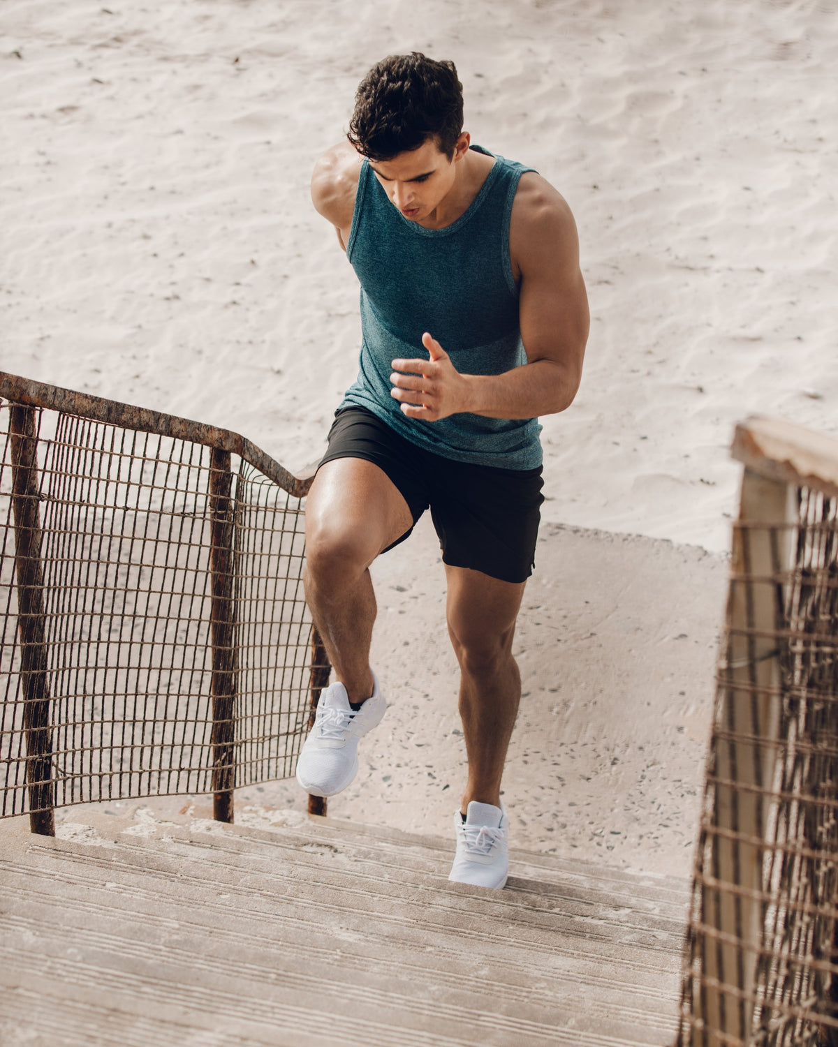 Young, fit man running up stairs on the beach. Representing Aminocare® A10 wellness supplement and mens health month in June.