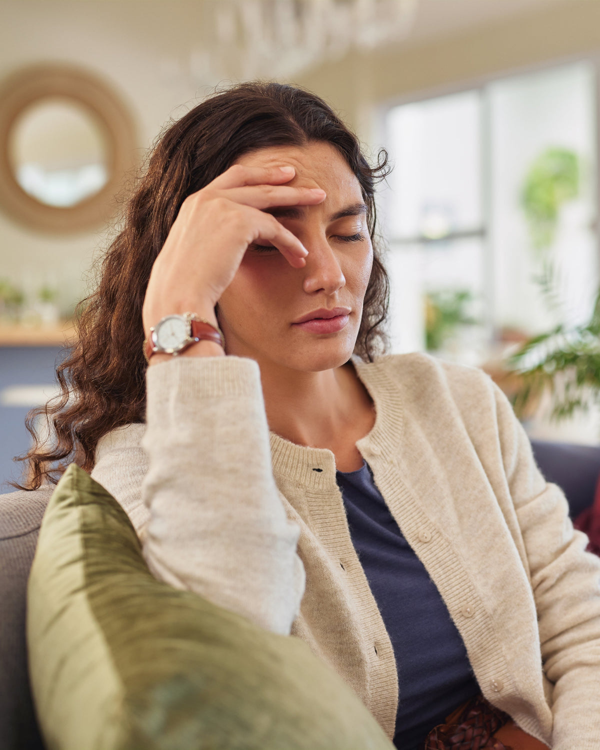 Woman looking tired and holding her head, representing stress, fatigue, and nervous system imbalance related to magnesium deficiency.