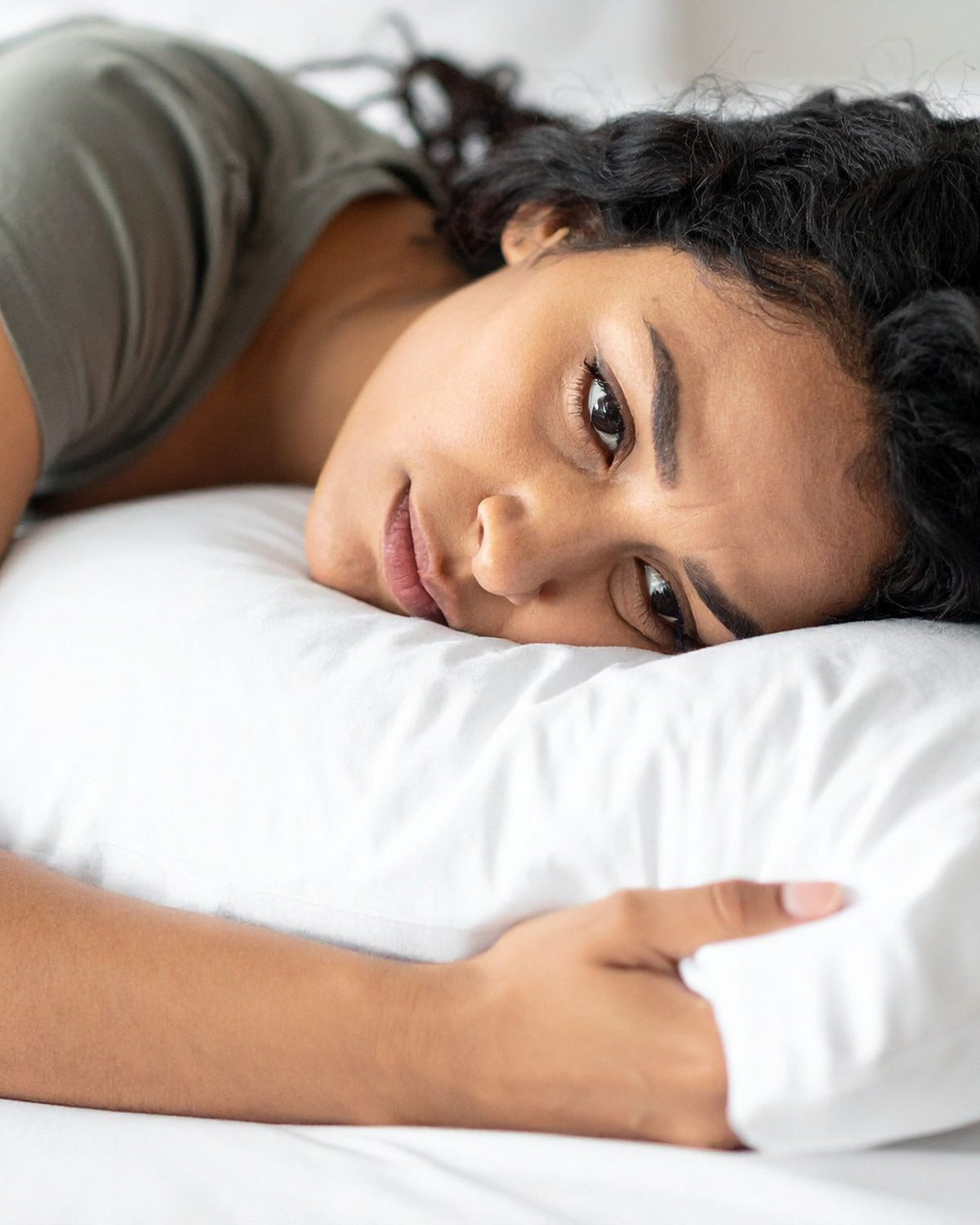 Woman laying on pillow with concerned look on her face representing AMINOCARE® AminoMag sleep support