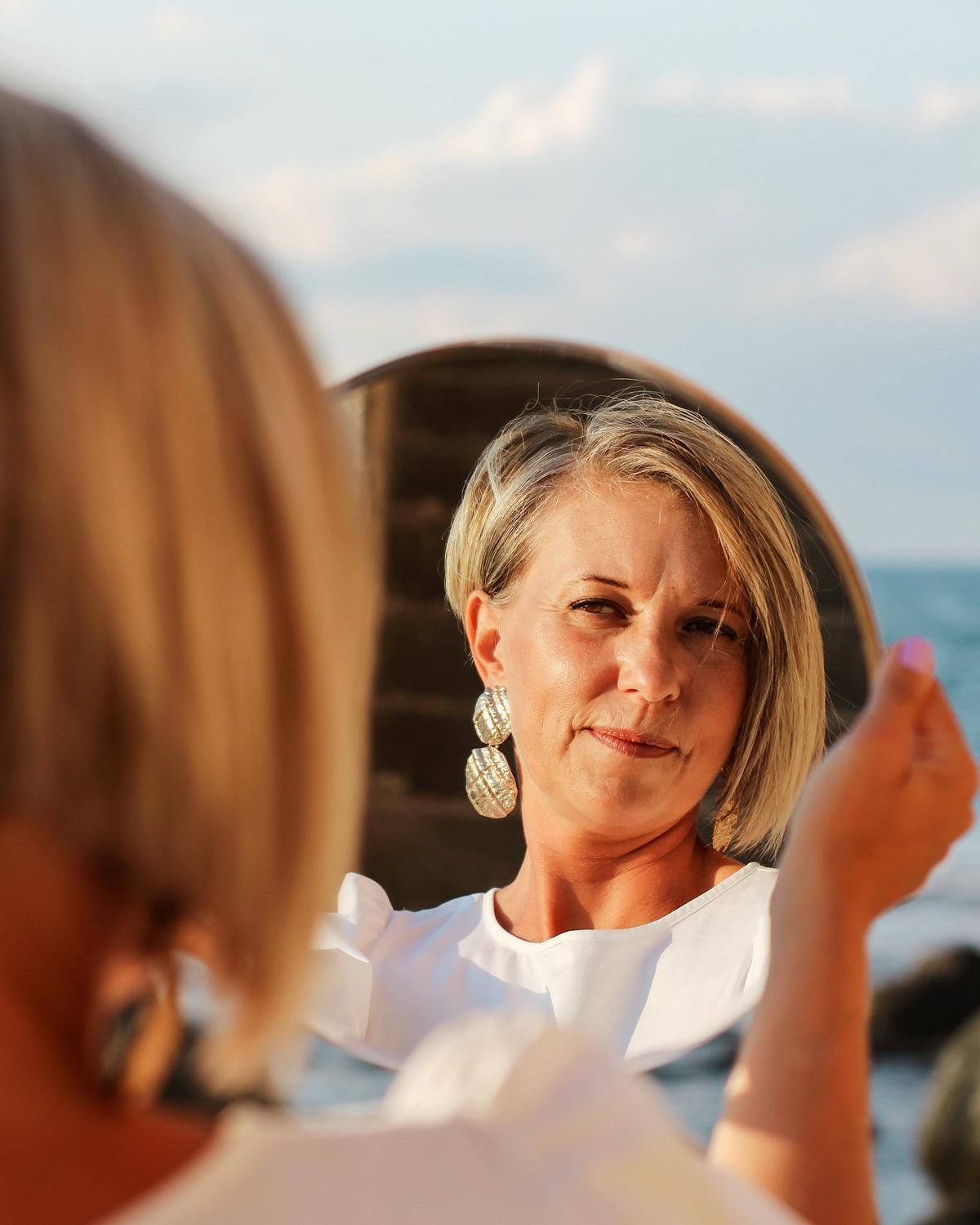 Woman looking in mirror with a calm, confident expression, representing hormone balance and overall wellness support by Aminocare® DIM.