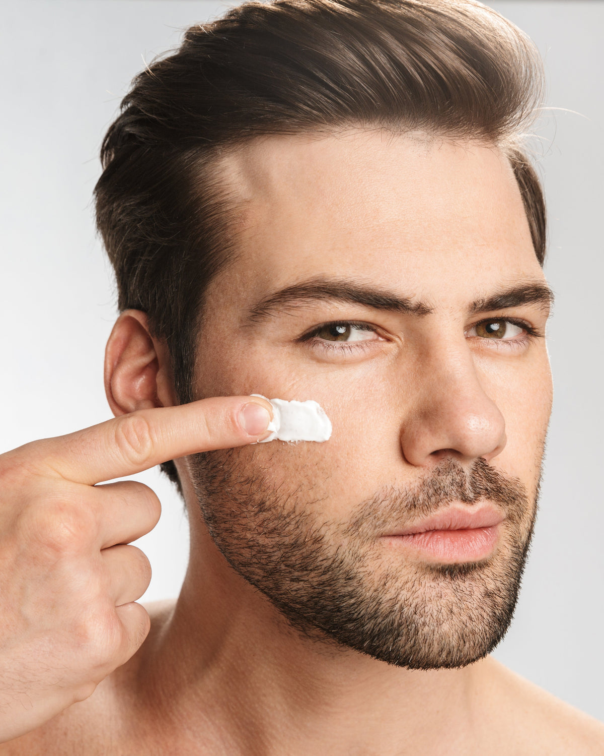 Man rubbing face cream on his cheek highlighting Aminocare® Fragrance-Free Cream