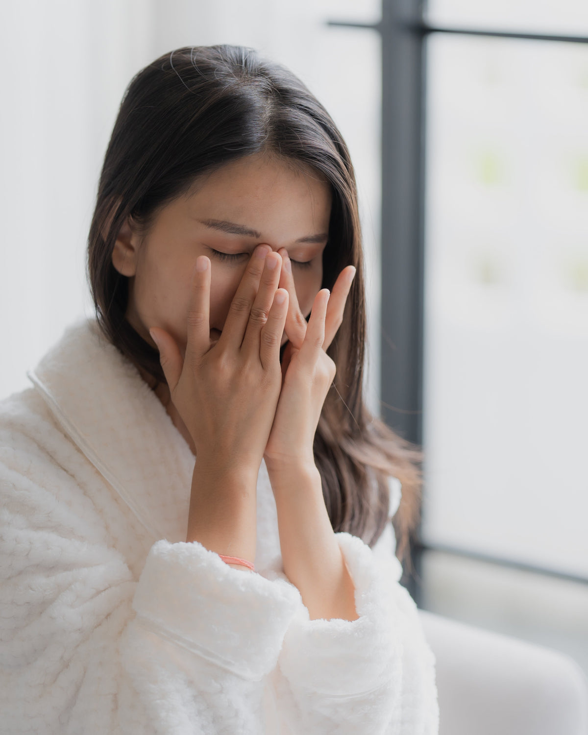 Woman holding her face representing a headache. Support from Aminocare® AminoMag supplement